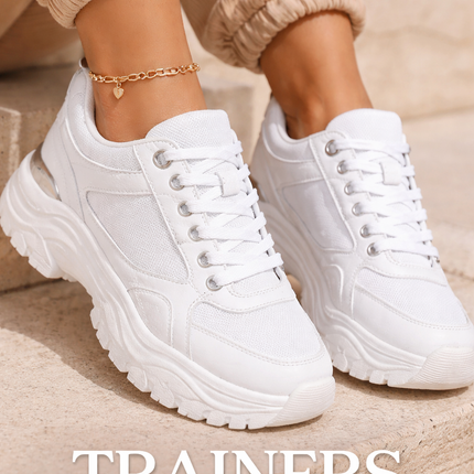 Close up of white chunky trainers worn with casual outfit on outdoor steps