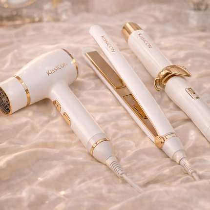Luxury hair styling tools including hair dryer, straightener and curling wand in white and gold design displayed on satin background – KissICON styling collection