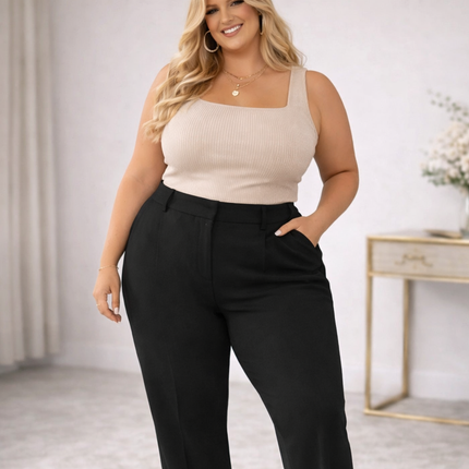 Plus size blonde woman wearing high waisted black trousers and fitted top in a neutral indoor setting